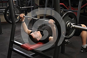 Young man doing bench press workout in gym