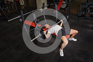 Young man doing bench press workout in gym