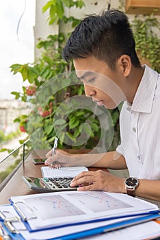 Young man doing calculation on calculator