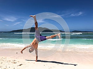 Young man doing a cartwheel at a tropical beach in Seychelles