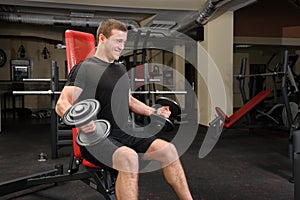 Young man doing Dumbbell Biceps workout in gym