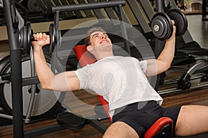 Young man doing Dumbbell Incline Bench Press workout in gym