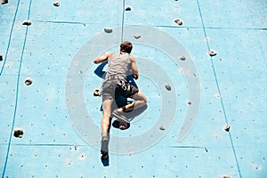 Young man doing exercise in mountain climbing on practice wall