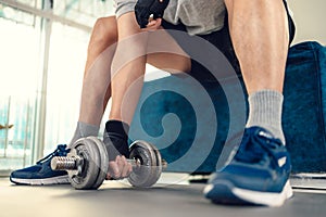 Young man doing exercises biceps with dumbbell on yoga mat in living room at home. Fitness, workout and traning at home concept