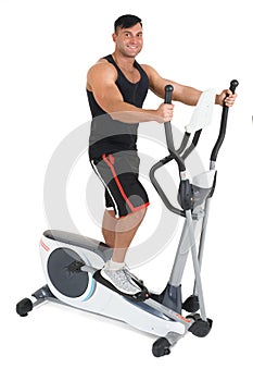 Young man doing exercises on elliptical cross trainer