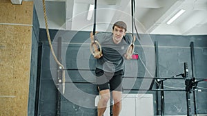 Young man doing exercises on still rings training in gym during crossfit practice