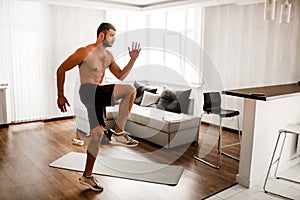 Young man doing exercising at home on the couch. Hardwoking t-shirtless guy sportsman in workout activity at his