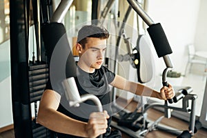 Young man doing fitness exercises on home gym chest press machine.Making an effort and training for fit toned summer body shape.