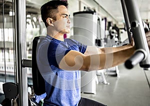 Young man Doing Heavy Weight Exercise For Chest On Machine With Cable In The Gym