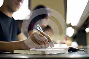 Young man doing homework and studying in college library