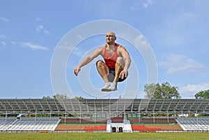 a young man doing a jump up workout on the green lawn of the city stadium