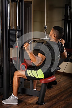 Young man doing lats pull-down workout