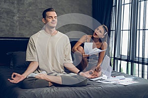 Young man doing mindfulness meditation ignoring his wife. Unveiling