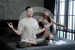 Young man doing mindfulness meditation ignoring his wife. Unveiling