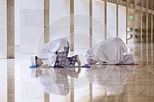 Young man doing prays with his wife in the mosque