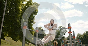 Young man doing pull ups on a bar in the park