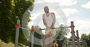 Young man doing pull ups on a bar in the park