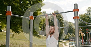 Young man doing pull ups on a bar in the park