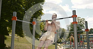 Young man doing pull ups on a bar in the park