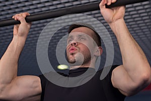 A young man doing pull ups in the Gym