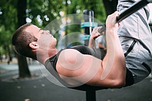 Young man doing pull ups on horizontal bar outdoors, workout, sp