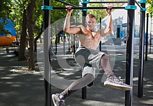 Young man doing pull ups on horizontal bar outdoors, workout, sp
