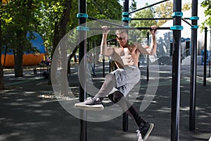 Young man doing pull ups on horizontal bar outdoors, workout, sp