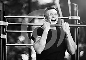Young man doing pull ups on horizontal bar outdoors, workout, sport concept