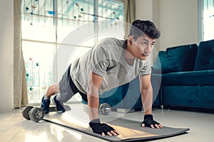 Young man doing push up and exercises on yoga mat in living room at home. Fitness, workout and traning at home concept