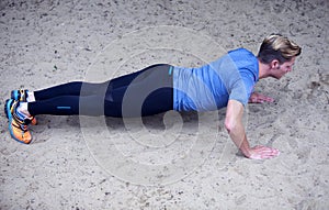 Young man doing pushups in the sand