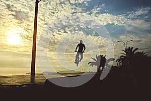 Young man doing ramp jump stunt on bmx bicycle on sunset. Silhouette unrecognizable of a guy with a bmx bicycle. BMX