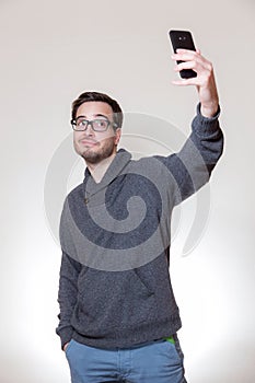 A young man is doing a selfportrait with his cellphone