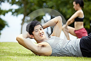 Young man doing sit-ups in park