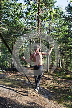 Young man doing slackline rodeo in forrest outside sports activities, lifestyle people concept