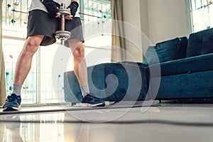 Young man doing squat exercises with dumbbell on yoga mat in living room at home. Fitness, workout and traning at home concept