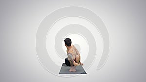 Young man doing squat with twist and bend yoga on gradient background.