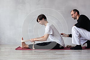 Young man doing stretching exercise with belt