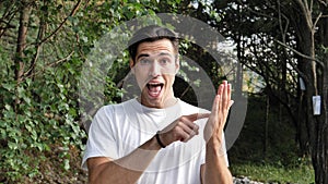 Young man doing Text Me sign, in nature