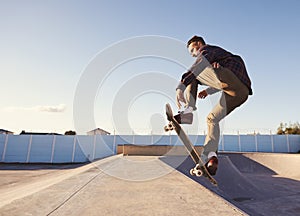 A rad day at the skate park. A young man doing tricks on his skateboard at the skate park.