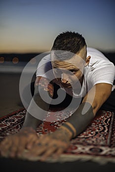 Young man doing yoga on the beach at sunset