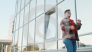 Young man with down syndrome in checkered shirt happy dancing outdoors in the city