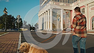 Young man with down syndrome in checkered shirt walking with dog outdoors in the city