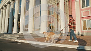 Young man with down syndrome in checkered shirt walking with dog outdoors in the city