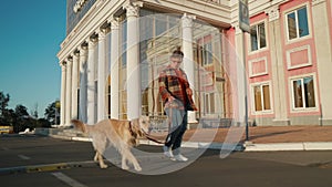 Young man with down syndrome in checkered shirt walking with dog outdoors in the city