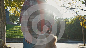Young man with down syndrome in checkered shirt walking with dog outdoors in the park