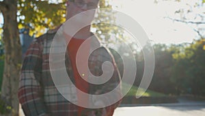 Young man with down syndrome in checkered shirt walking with dog outdoors in the park