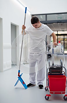 Young man with down syndrome working in a hospital as cleaner. Concpet of integration people with disability into