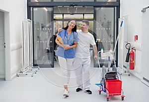Young man with down syndrome working in a hospital as cleaner, talking to nurse, having fun. Concpet of integration