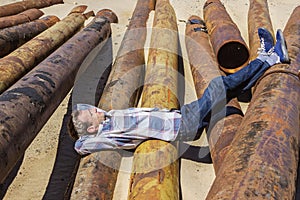 Young man dozed off, lying on metal pipes