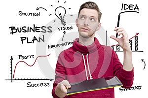 Young man with drawing pad and pen imagining business plan.